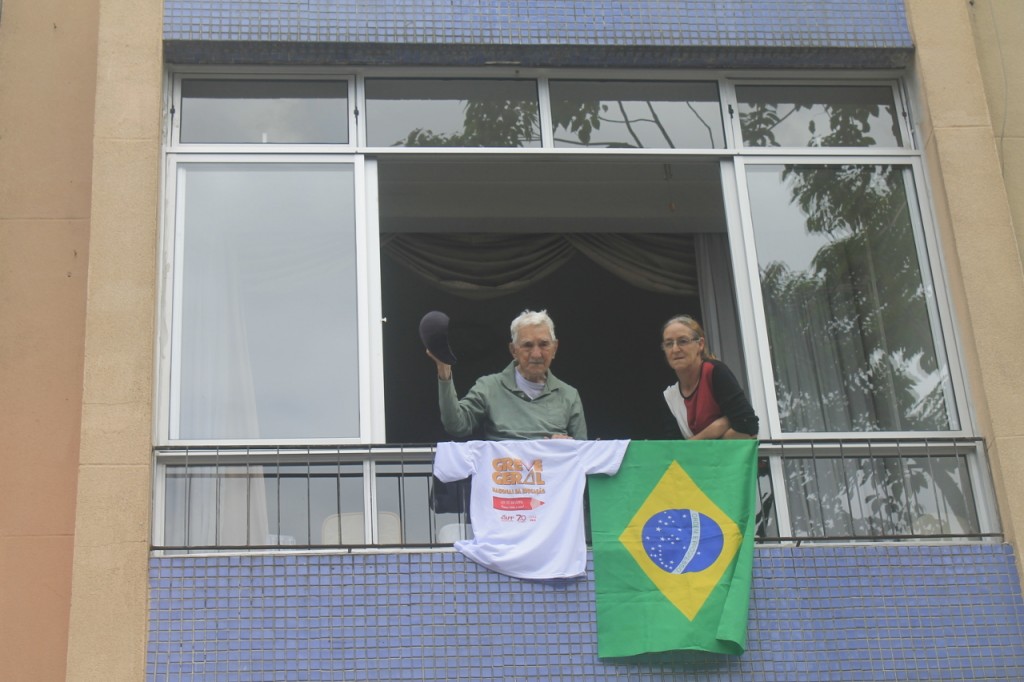 Aposentado, da sua janela, vê a caminhada passar. E apoia. Foto de Lindrielli Rocha